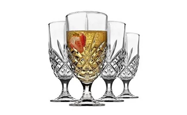 Four crystal champagne glasses on a white background, one filled with champagne and a strawberry.