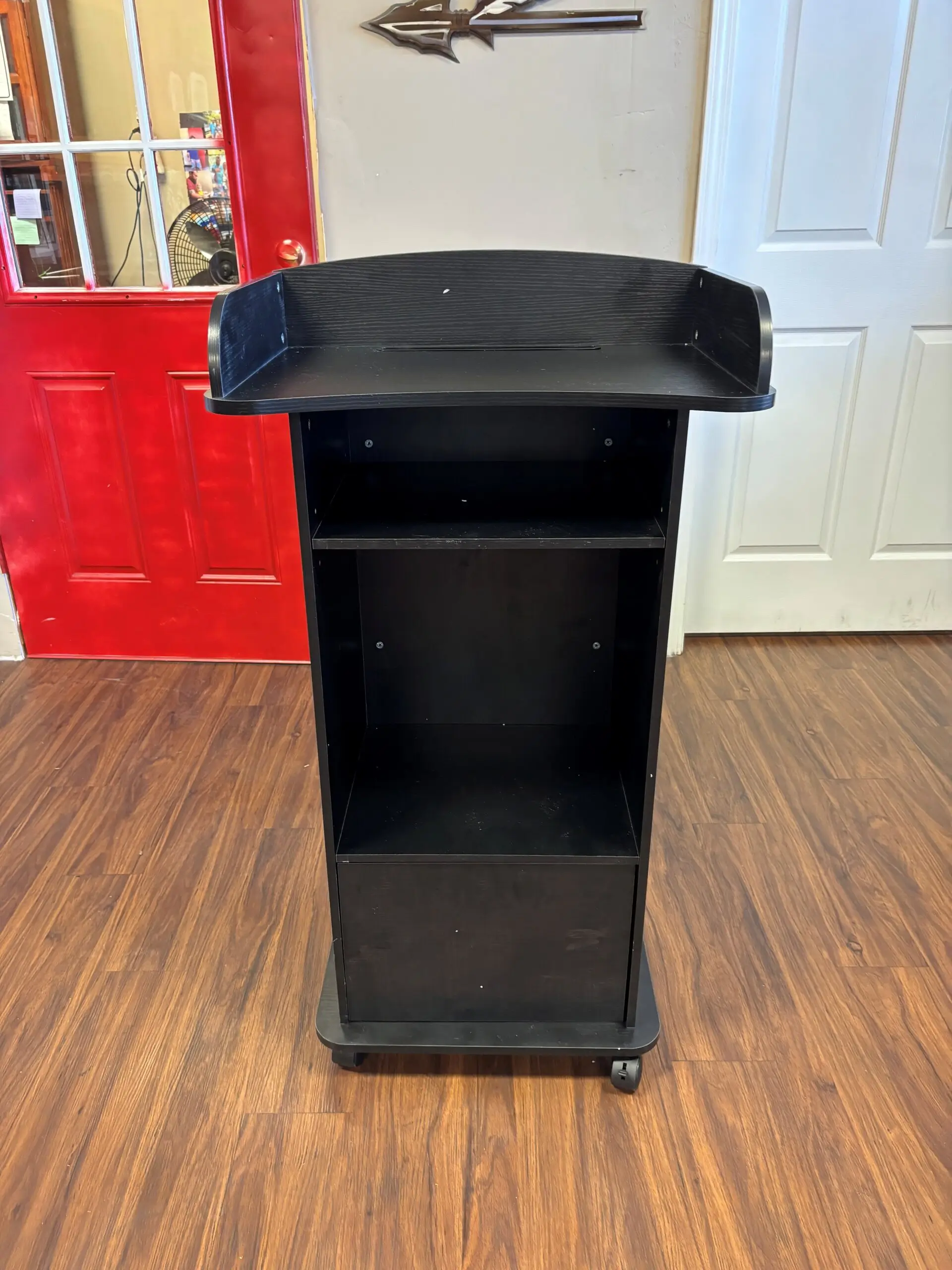 Black rolling podium on wooden floor.