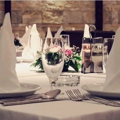 Elegantly set dining table with folded white napkins, silverware, and a small floral centerpiece in a restaurant.