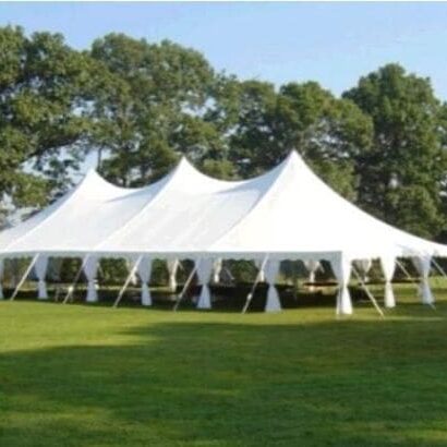 Large white event tent set up on a green lawn, under clear skies.